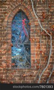 excellent image of a stained glass church window with last spray of autumn red leaves. the window