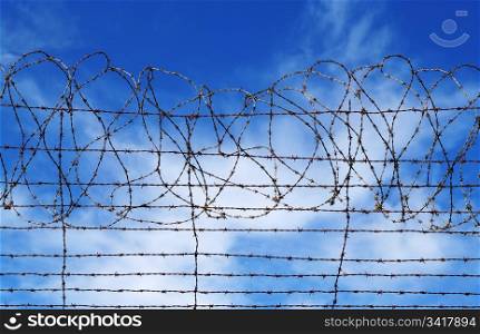 excellent image of barbed wire rolls in front of blue sky