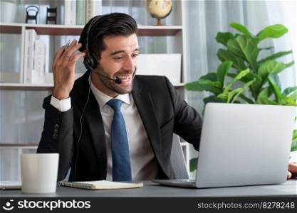 Excited and happy businessman dressed in black formal suit, raise his arm in celebratory gesture at office desk. Successfully call center or telesales operator celebrate in workplace. Fervent. Excited and happy businessman dressed in black formal suit. Fervent