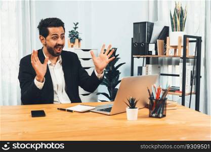 Excited and happy businessman dressed in black formal suit, raise his arm in celebratory gesture at his office desk, after successful job promotion, energy and joy as business winner. Fervent. Excited and happy businessman dressed in black formal suit. Fervent
