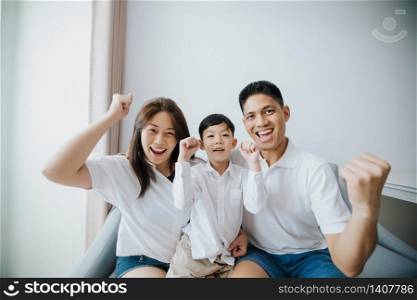 Excited and Happy family with arms raised while watching television at home
