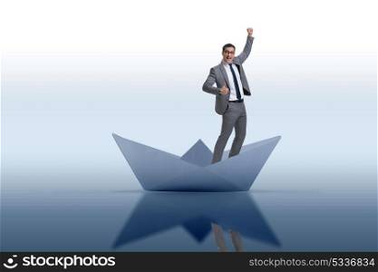 Excited businessman riding paper ship boat