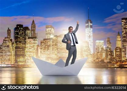 Excited businessman riding paper ship boat