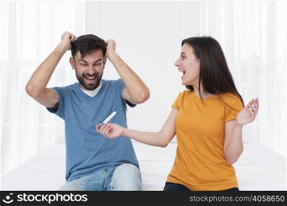 excited couple holding pregnancy test