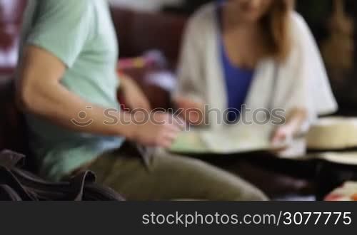 Excited couple planning romantic trip using map while sitting on floor in room. Attractive smiling woman pointing places to visit with finger on the map while boyfriend gesturing, expressing his expectations. Travel, tourism and vacation concept.