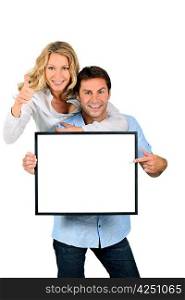 Excited couple pointing to a blank sign
