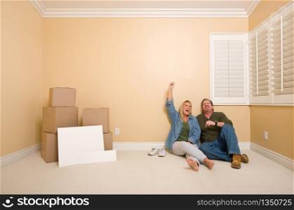 Excited Couple Relaxing on Floor Near Boxes and Blank Real Estate Signs in Empty Room