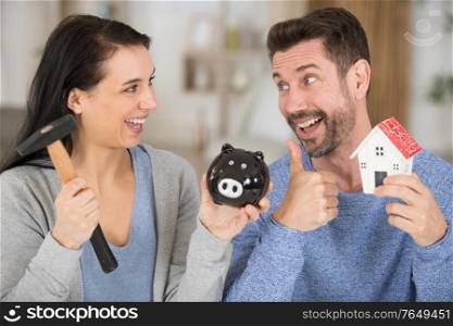 excited couple smashing piggybank to invest in a house