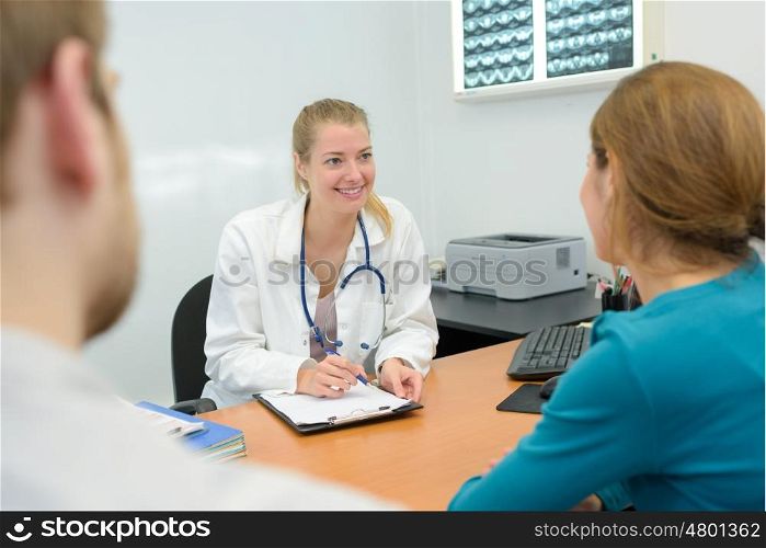 excited couple talking to a doctor sitting at desk