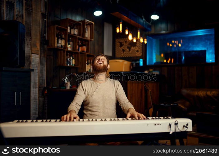 Excited emotional pianist playing synthesizer and singing loudly. Male compositor performance. Excited emotional pianist playing synthesizer and singing