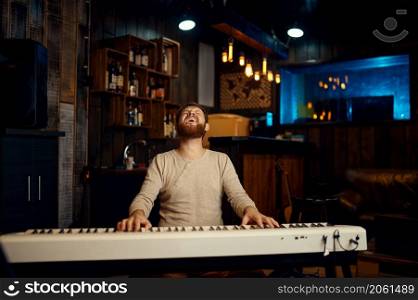 Excited emotional pianist playing synthesizer and singing loudly. Male compositor performance. Excited emotional pianist playing synthesizer and singing