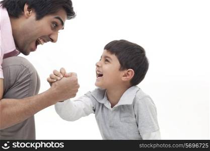 Excited father playing arm wrestle with his son over white background