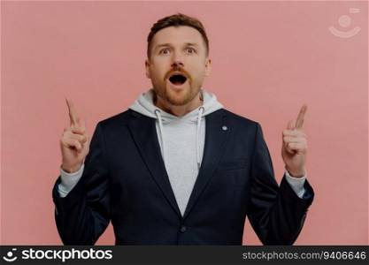 Excited ginger guy in trendy clothes pointing up, amazed. Promotion and discount concept.