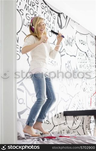 Excited girl listening music while singing into hairbrush at home