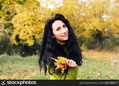 Excited happy fall woman smiling joyful and blissful holding autumn leaves outside in colorful fall forest. Young woman in beautiful autumn park, concept autumn