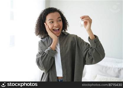 Excited happy mixed race teen girl tenant showing keys to new home. Modern joyful young lady delighted with moving and purchasing own apartment. Real estate rental service advertising.. Excited happy mixed race girl tenant shows keys to new home. Real estate rental service advertising