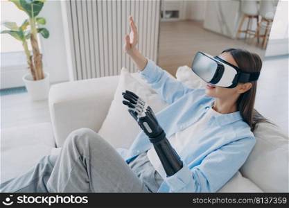 Excited lady touches 3d vision. Happy disabled european girl with artificial robotic arm in virtual reality glasses gets treatment. Psychological rehabilitation for handicapped. Cyber technology.. Excited lady touches 3d vision. Happy disabled european girl with artificial robotic arm.