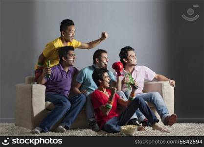 Excited male friends cheering out while watching boxing match together at home