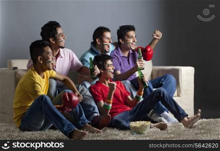 Excited male friends watching boxing match together at home