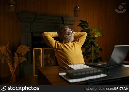 Excited mature man feeling satisfaction relaxed sitting at table with laptop in home office. Happy dreamy senior male holding hands behind head looking up with smile on face think of future success. Excited mature man feeling satisfaction sitting at table in home office