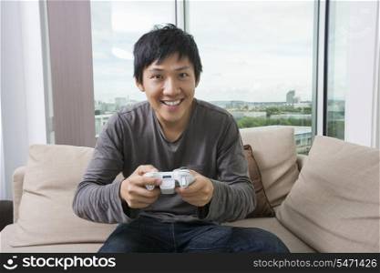 Excited mid adult man playing video game on sofa