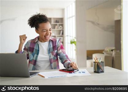 Excited mixed race teen girl student received good news email on laptop, celebrates personal achievement, success. Joyful biracial schoolgirl got good exam scores, makes yes gesture, screaming.. Excited mixed race teen girl student got good news email on laptop celebrates personal achievement