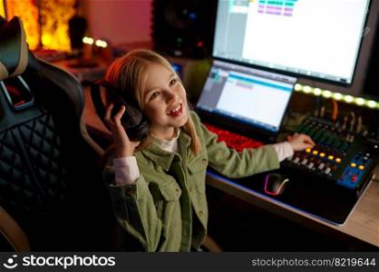 Excited successful young girl preteen child audio engineer mixing sound inside sound record studio. Young audio engineer mixing sound at production house