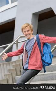 Excited teenage boy sliding down handrail on university stairway