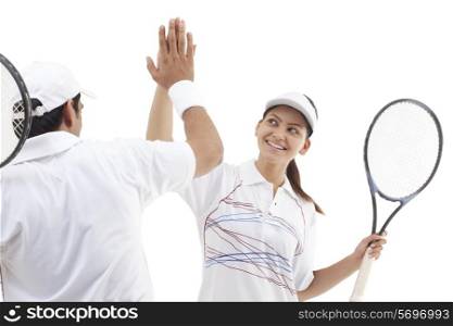 Excited tennis players doing high five isolated over white background