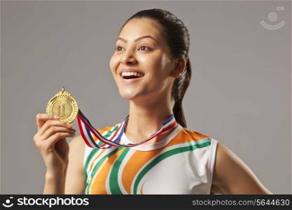 Excited woman holding gold medal isolated over gray background