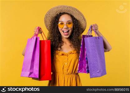 Excited woman with colorful paper bags after shopping on yellow studio background. Concept of seasonal sale, purchases, spending money on gifts. High quality photo. Excited woman with colorful paper bags after shopping yellow studio background