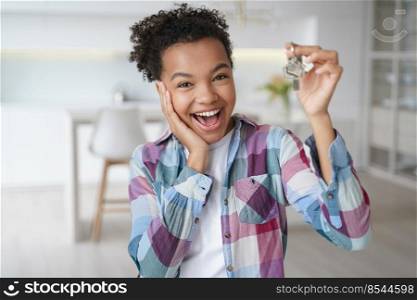 Excited young african american teen girl tenant showing keys of first new house. Happy biracial female delighted with buying or renting apartment holds home key. Relocation, real estate rent service. Excited african american teen girl tenant showing keys of first new house. Real estate rent service