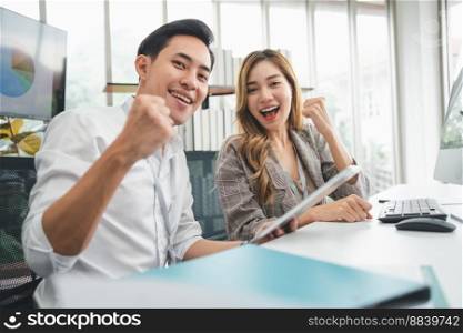 Excited young Asian startup business team celebrate successful and victory and hand up at office and looking at camera, happy euphoric proud Asian male and female professional winner feel overjoyed