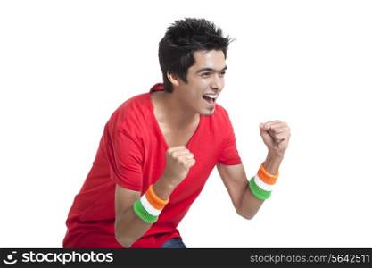 Excited young boy looking away while cheering with clenched fists over white background