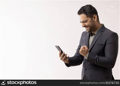 Excited young businessman looking at cell phone