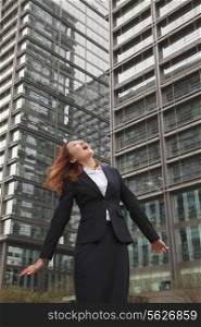 Excited young businesswoman looking up with wind blowing in her hair
