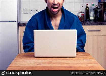 excited young man with laptop in kitchen