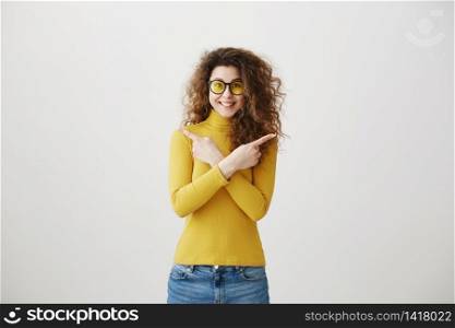 Excited young woman pointing her finger towards blank space isolated over grey background. Excited young woman pointing her finger towards blank space isolated over grey background.