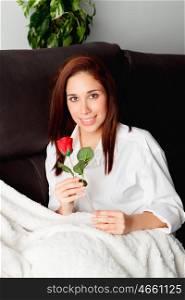 Excited young woman with a red rose on her couch&#xA;