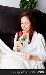 Excited young woman with a red rose on her couch&#xA;