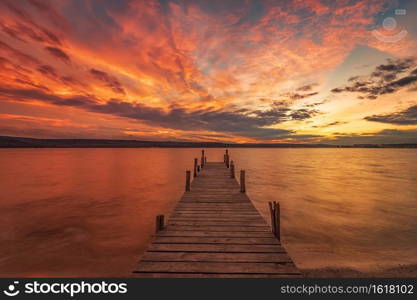 Exciting colorful sunset view from the shore with a wooden pier