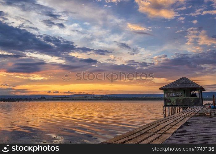 Exciting long exposure landscape on a lake with a wooden pier and small house in the end