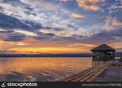 Exciting long exposure landscape on a lake with a wooden pier and small house in the end