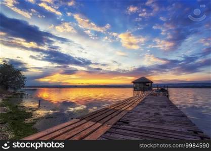 Exciting long exposure landscape on a lake with a wooden pier and small house in the end.