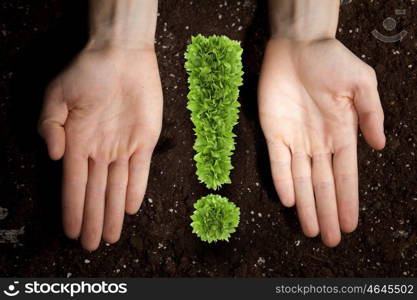 Exclamation nature green mark. Exclamation green mark in male palms on soil background