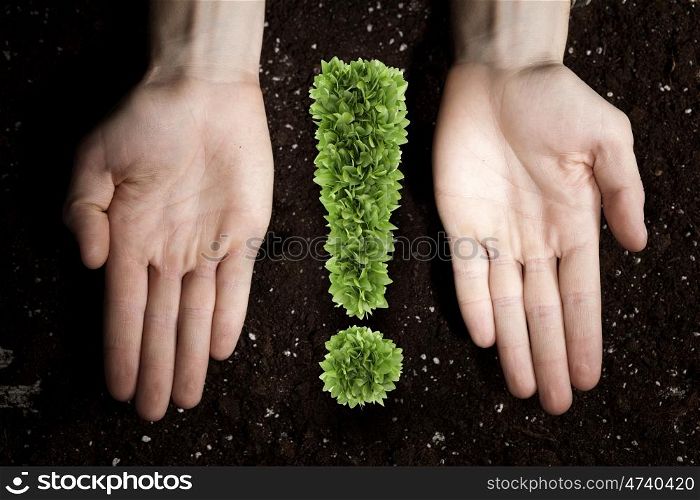 Exclamation nature green mark. Exclamation green mark in male palms on soil background