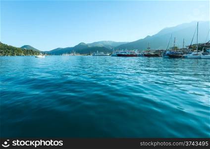 Excursion ships and tallships in bay. Hazy summer Lefkada coast landscape (Nydri, Greece, Ionian Sea).