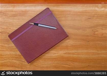 Executive notepad with pen on cherry wood desktop with plenty of copy space.