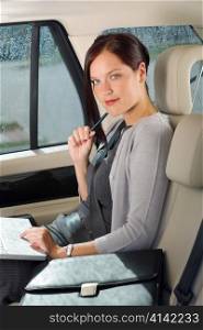 Executive woman manager working on laptop sitting car leather backseat