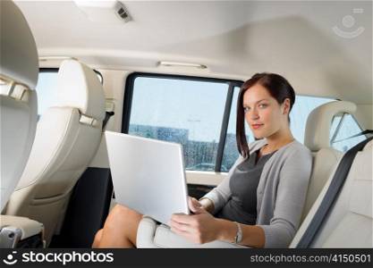 Executive woman manager working on laptop sitting car leather backseat